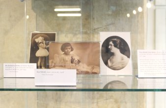 Farbfoto, drei historische Fotos hinter Glas, vor jedem Foto eine kleine Texttaffel