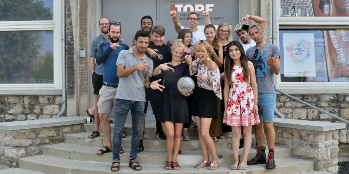 einer Gruppe junger Menschen steht auf einer Treppe und hält einen bunten Fußball in den Händen