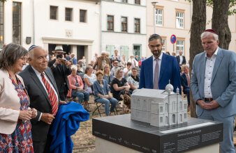 mehrere Manschen stehen vor einem Hausmodell