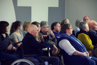 Foto: Konzert im Erinnerungsort © Stadtverwaltung Erfurt/Boris Hajduković Gruppe von Menschen auch im Rollstuhl sitzen und hören einem Konzert zu.
