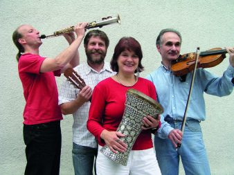 Farbfoto von drei Männern und einer Frau mit Instrumenten.