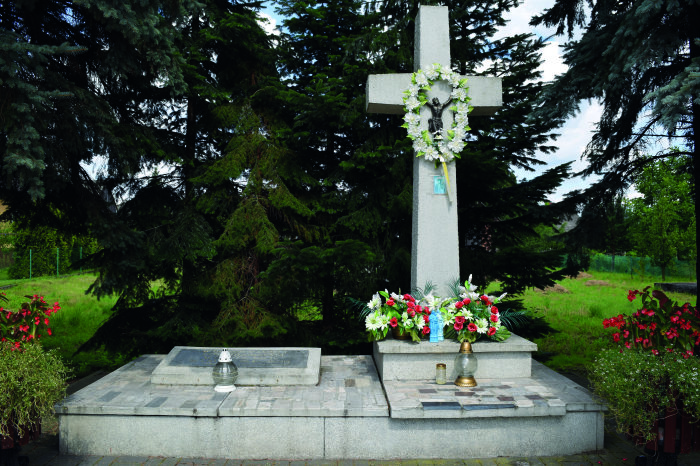 Ein Kreuz und eine Gedenktafel mit Blumen geschmückt.