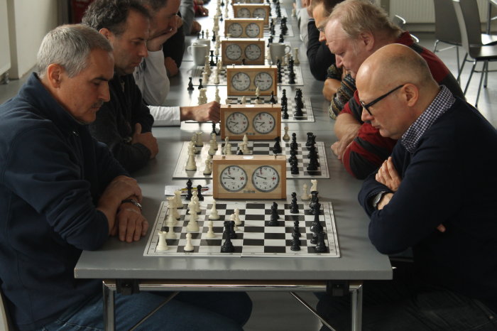 Männer sitzen an Tischen und spielen Schach