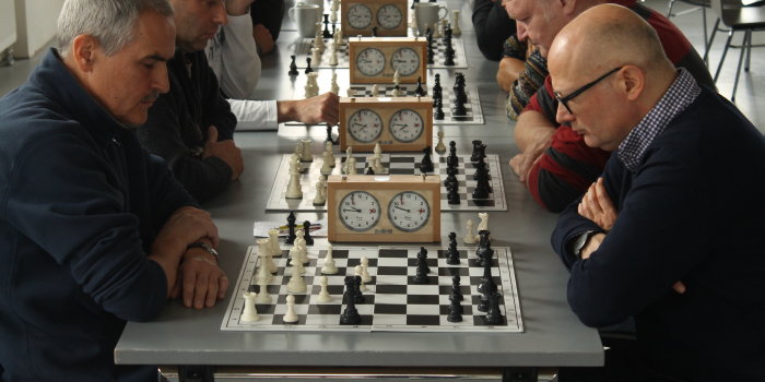 Männer sitzen an Tischen und spielen Schach