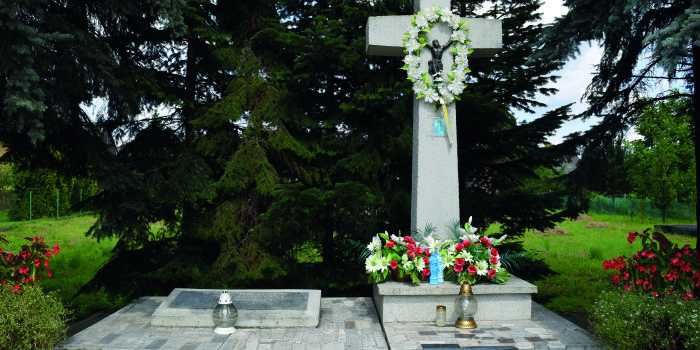 Ein Kreuz und eine Gedenktafel mit Blumen geschmückt.