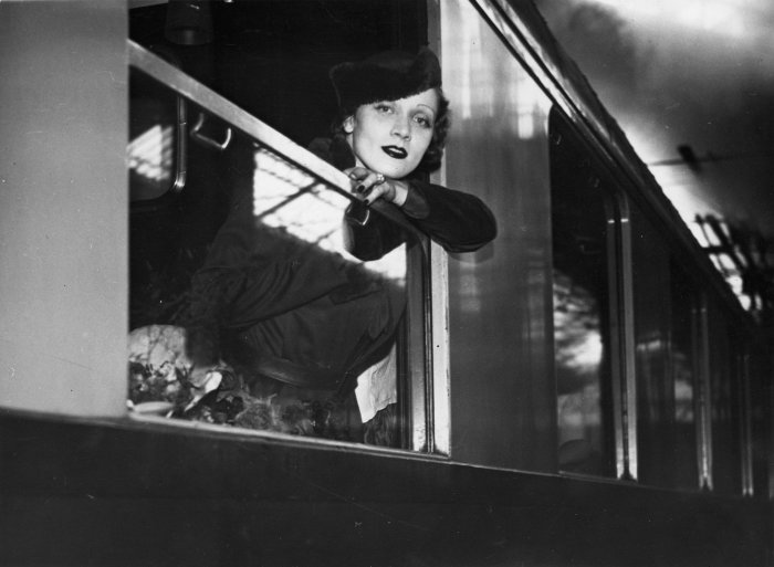 Eine Frau lehnt sich aus einem geöffneten Zugfenster. 