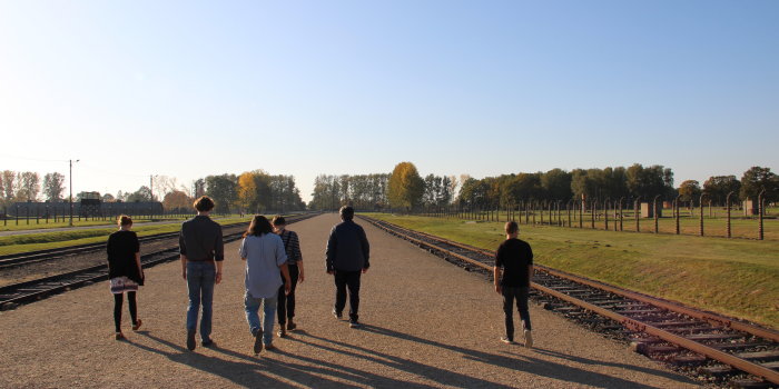 Six people walk along a gravel path.