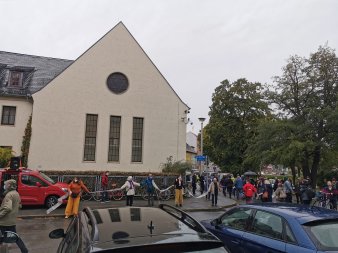 Mit Stoffbahnen bilden Menschen eine Kette um ein Gebäude.