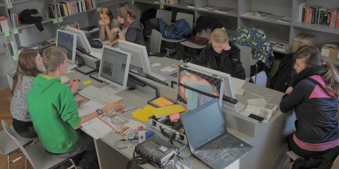 Personen sitzen vor Bildschirmen in einer Bibliothek.