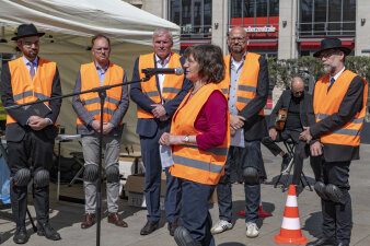 sechs Personen mit Warnweste und eine Person hält eine Rede