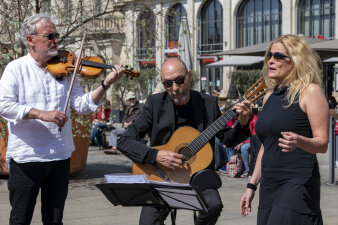 drei Personen ein Mann spielt Geige ein Mann Gitarre und eine Frau singt dazu
