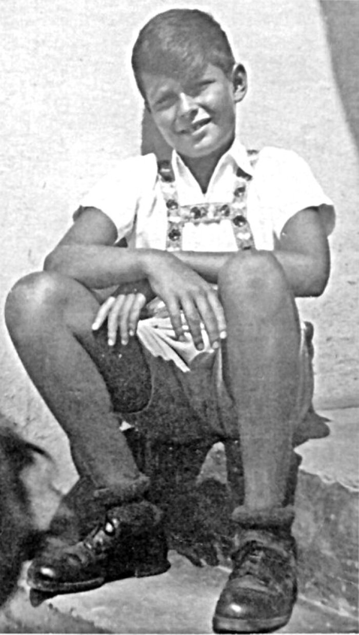 Pavel Taussig 1944 Schwarz weiß Foto eines Jungen mit kurzer Hose und kurzärmligen weißen Hemd der auf einer Stufe sitzt