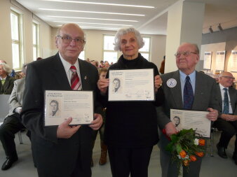 Einen Frau und zwei Männer, jeweils mit einer Urkunde des Jochen-Bock-Preises