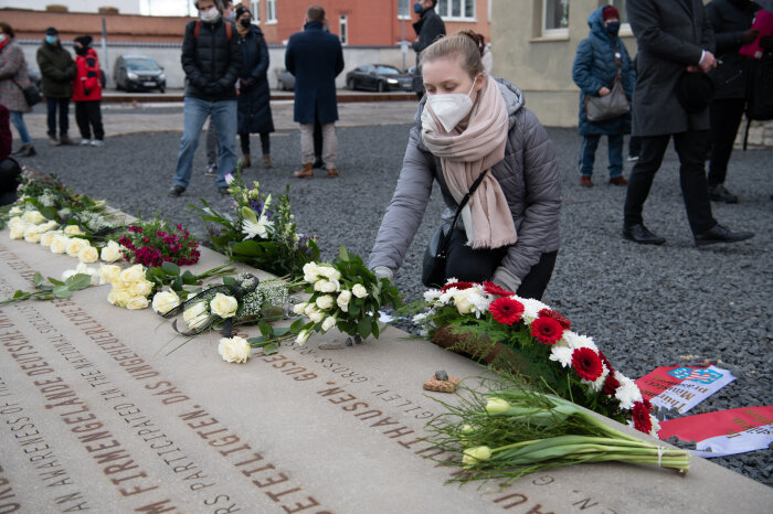 Eine Frau legt Blumen auf eine Steinplatte