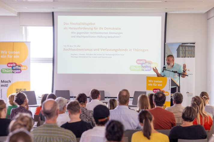 Mehrere Personen bei einer Veranstaltung und ein Mann der zu ihnen spricht