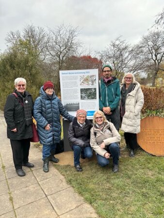 Sechs Personen an einer Ausstellungstafel