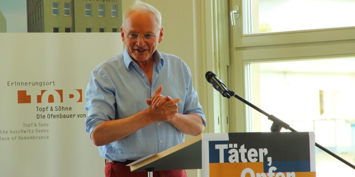 Mann hinter einem Mikrofon der eine Rede hält