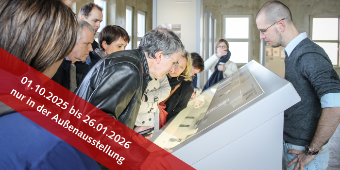 Personen in einer Ausstellung die sich eine Vitrine ansehen
