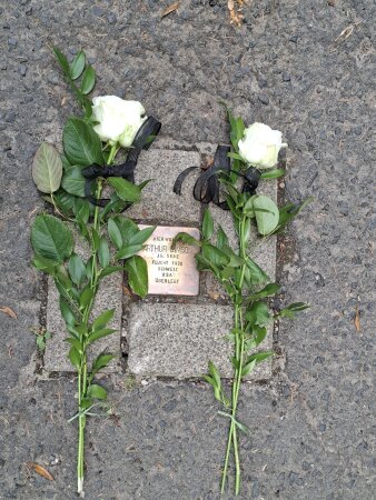 Stolperstein Arthur Simson in Suhl mit zwei weißen Rosen daneben liegend