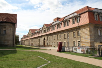 langgestrecktes Gebäude mit Weg und Wiese im Vordergrund
