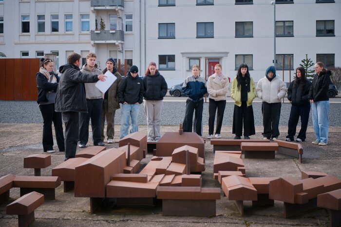 Gruppe steht vor Modell des Firmengeländes während der Guide etwas erklärt.