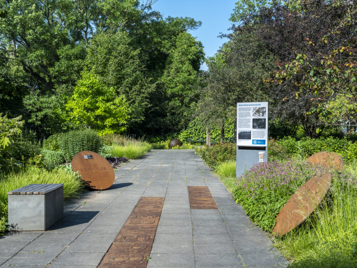 Park mit gepflasterten Weg, einer Stele und Kegeln