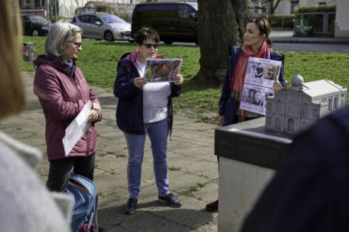 Drei Frauen mit Bildern in der Hand stehen neben einem Modell der alten Erfurter Synagoge