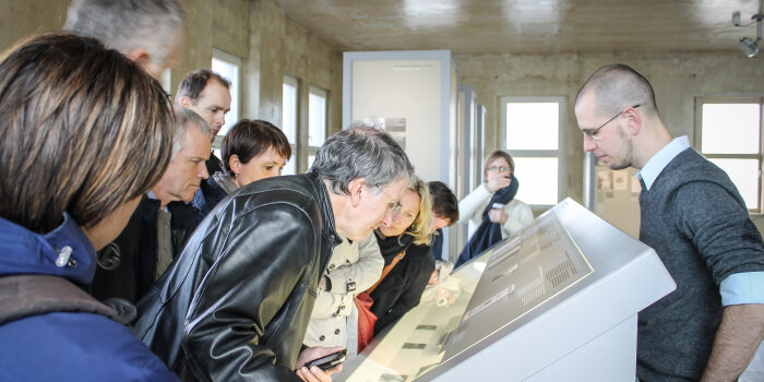 Gruppe steht mit Guide an Ausstellungspult