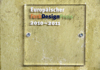 Farbfoto, gelbe Wand, auf der eine Plakette aufgeschraubt ist mit Schriftzug Europäischer Farbdesign-Preis 2010-2011