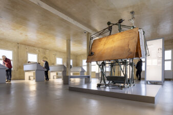 Zeichentisch und Vitrinen in einem Ausstellungsraum 