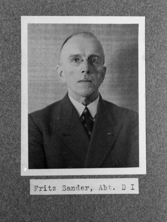 Schwarz-Weiß-Fotografie eines älteren Mannes im Anzug mit Krawatte, trägt Brille, unter der Fotografie in Druckschrift Fritz Sander, Abt. D 1