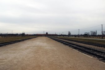 Farbfotografie, rechts und links Schienen, die im Bildzentrum zu einem Tor führen