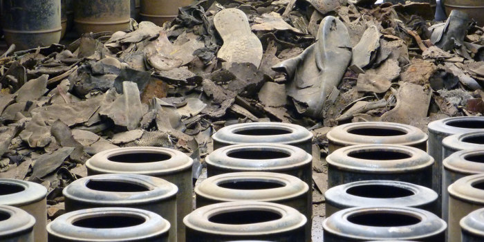 In the foreground several ash containers, in the background remains of clothes and shoes