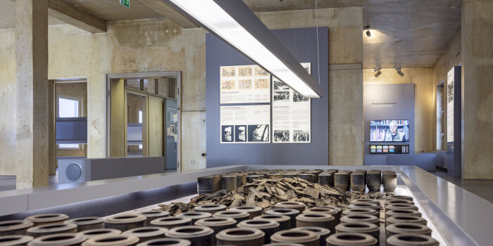 Ausstellungsraum mit verschiedenen Schautafeln, im Vordergrund stehen zahlreiche runde Gefäße