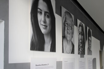 Ausdrucke von Schwarz-Weiß-Fotos und Texten hängen an den Wänden eines Raumes