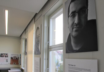 Ausdrucke von Schwarz-Weiß-Fotos und Texten hängen an den Wänden eines Raumes