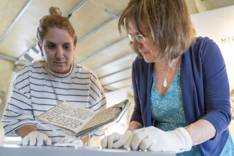 zwei Frauen mit Handschuhen stehen um ein Buch herum