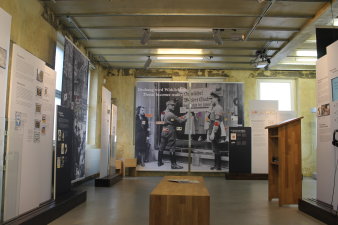 Blick in die Ausstellung "Angezettelt". Zu sehen sind Banner und Texttafeln sowie eine Bank und ein Stehpult.