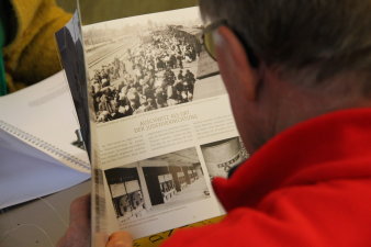 Farbfoto, Person hält aufgeschlagenes Buch in der Hand