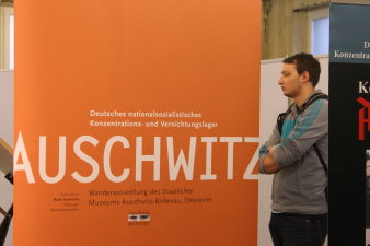 Farbfoto, orangenes Banner mit Schriftzug Deutsches nationalsozialistisches Konzentrations- und Vernichtungslager Auschwitz Wanderausstellung des Staatlichen Museums Auschwitz-Birkenau Oświęcim Schirmherr Bodo Ramelow Thüringer Ministerpräsident