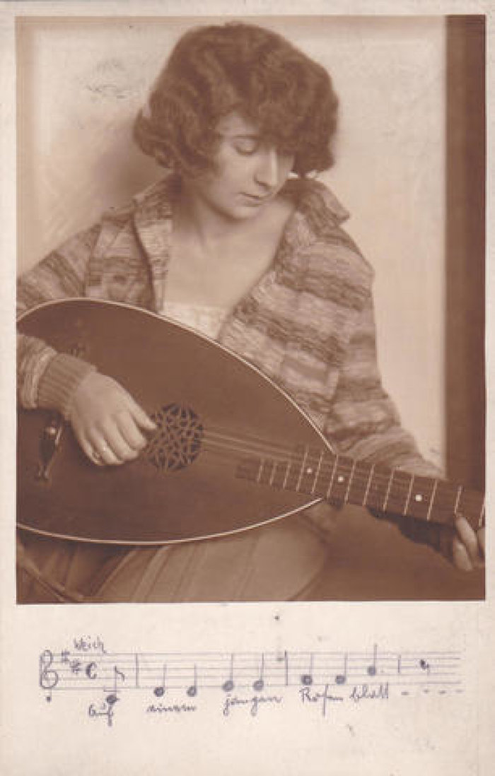 Eine Frau spielt eine Mandoline. Unter dem Bild stehen Noten und ein Liedtext.