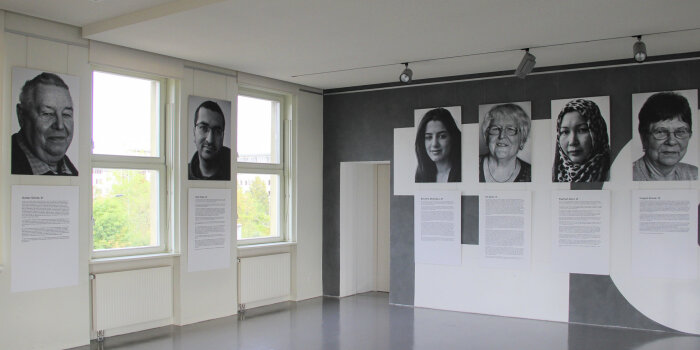 Ausdrucke von Schwarz-Weiß-Fotos und Texten hängen an den Wänden eines Raumes