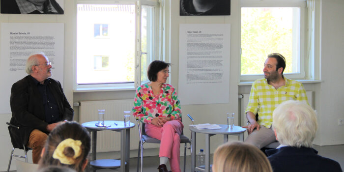 Drei Personen sitzen im Gespräche zur Eröffnungsveranstaltung der Ausstellung „Flüchtlingsgespräche“.