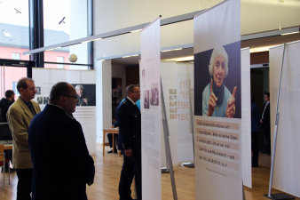 Farbfoto, mehrere bedruckte Banner im Raum, dazwischen Personen