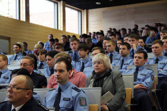 Farbfoto, sitzende Personen, die meisten in blauer Uniform