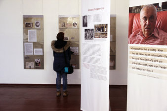 Farbfoto, mehrere bedruckte Banner und Tafeln im Raum, eine Person steht vor einer Tafel