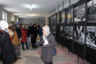 Farbfoto, Gruppe mit Kopfhörern in einem Raum mit großformatigen Fotos