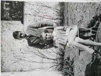 Historisches schwarz-weiß Foto von einem sitzenden Mädchen und einem dahinter stehenden Jungen. 