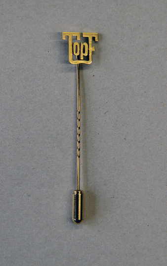 Farbfoto einer goldfarbenen Anstecknadel mit Topf-Logo