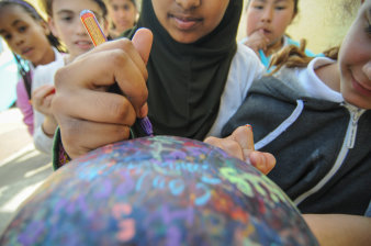 Farbfoto, junge Frau mit Kopftuch unterschreibt auf einem Ball